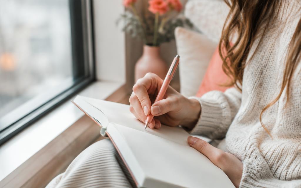 A person reflecting and writing in a journal