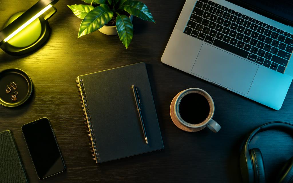 A focused workspace with a notebook, laptop, and coffee